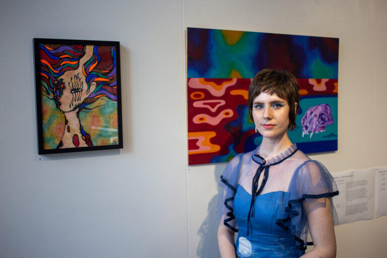 Image of Arielle at Hope Street Cafe, standing in front of her artworks.